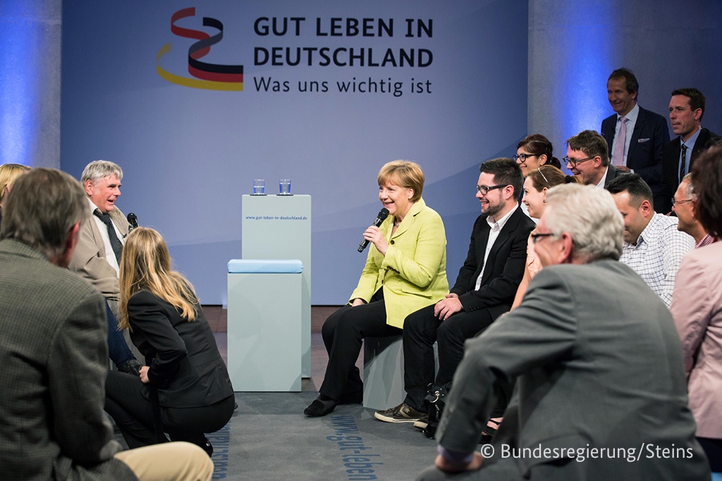 Foto von Angela Merkel im Gespräch mit den Teilnehmern.