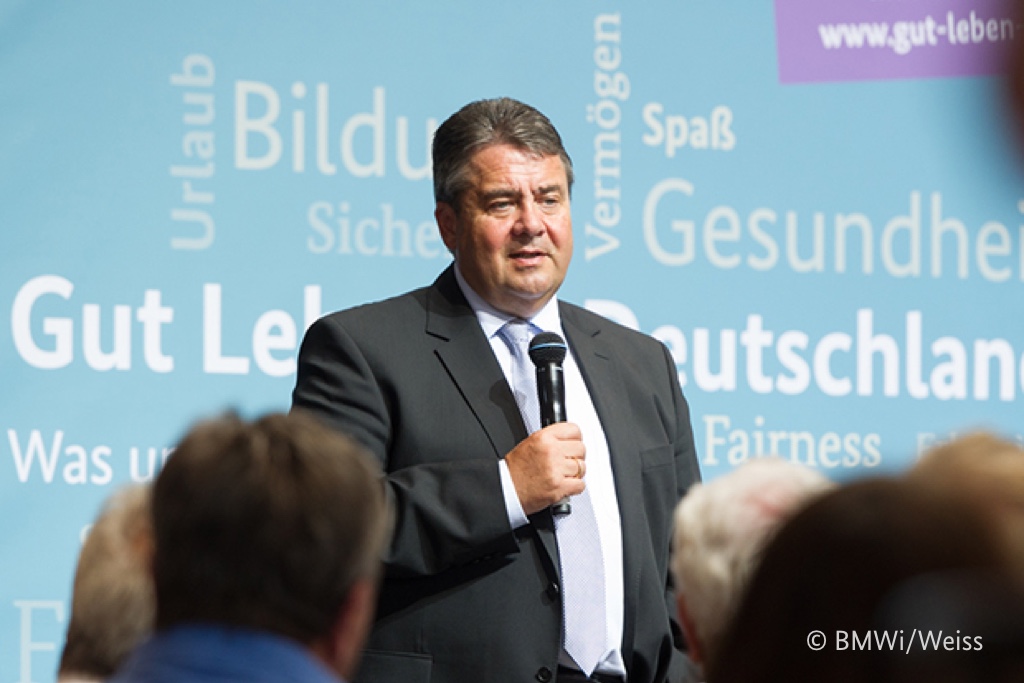 Foto von Sigmar Gabriel, der mit einem Mikrofon vor einer Gruppe von Menschen stehen.